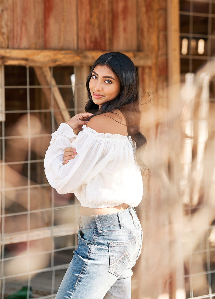 Girl posing in a barn for senior pictures in Parker Texas