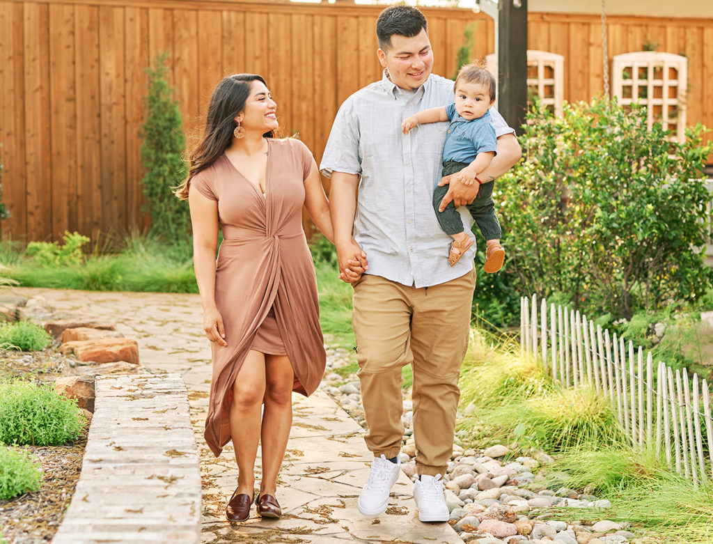 Family of three walking together in a garden